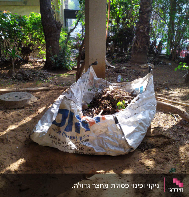 שק גדול מלא בעלים וענפים בגינה מוצלת